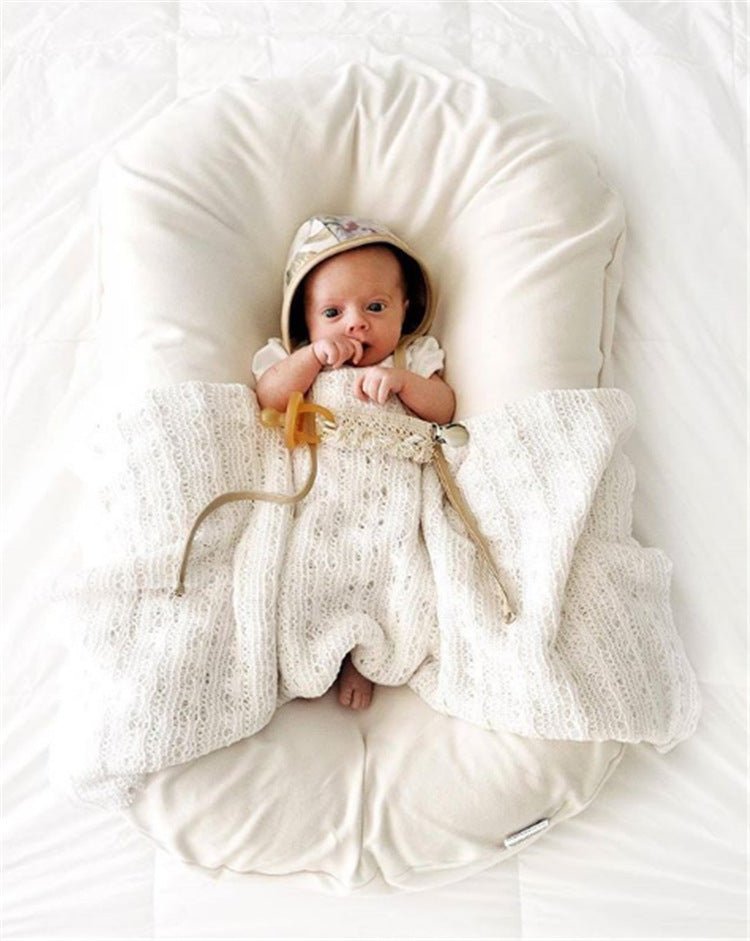 Ancient Energy baby nest bed for newborns: cream cotton travel crib with hood and knitted blanket.