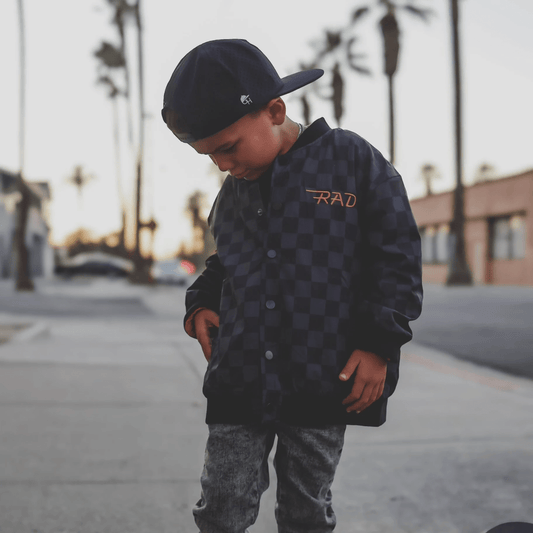 Kids waterproof letterman jacket by Little Rad Things with checkered pattern, featuring a durable, stylish design suitable for boys and girls.