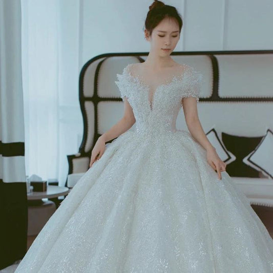 Off shoulder French main wedding dress by MANDOTOS featuring elegant lace details and a flowing silhouette.