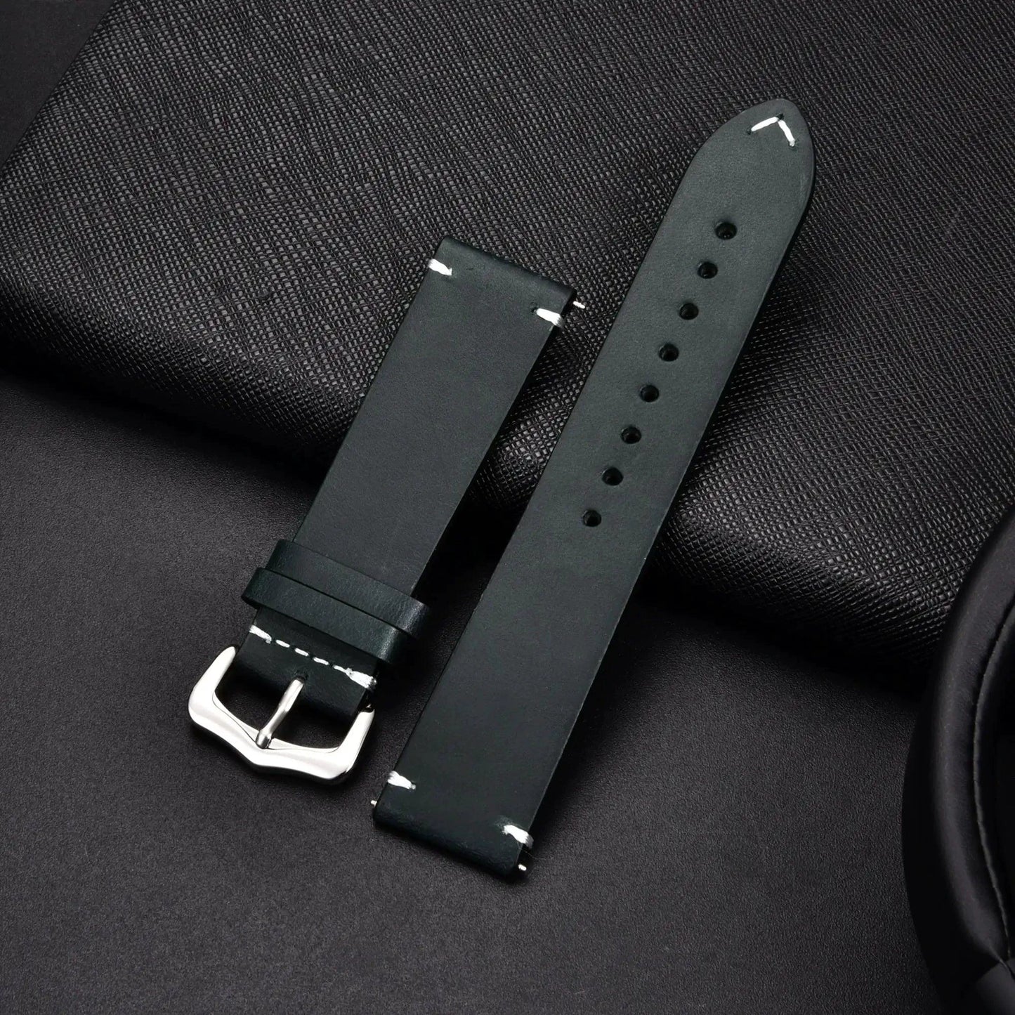 Elegant leather watch band by MANDOTOS, showing a close-up of the sleek, brown strap with stitching detail and polished metal buckle.