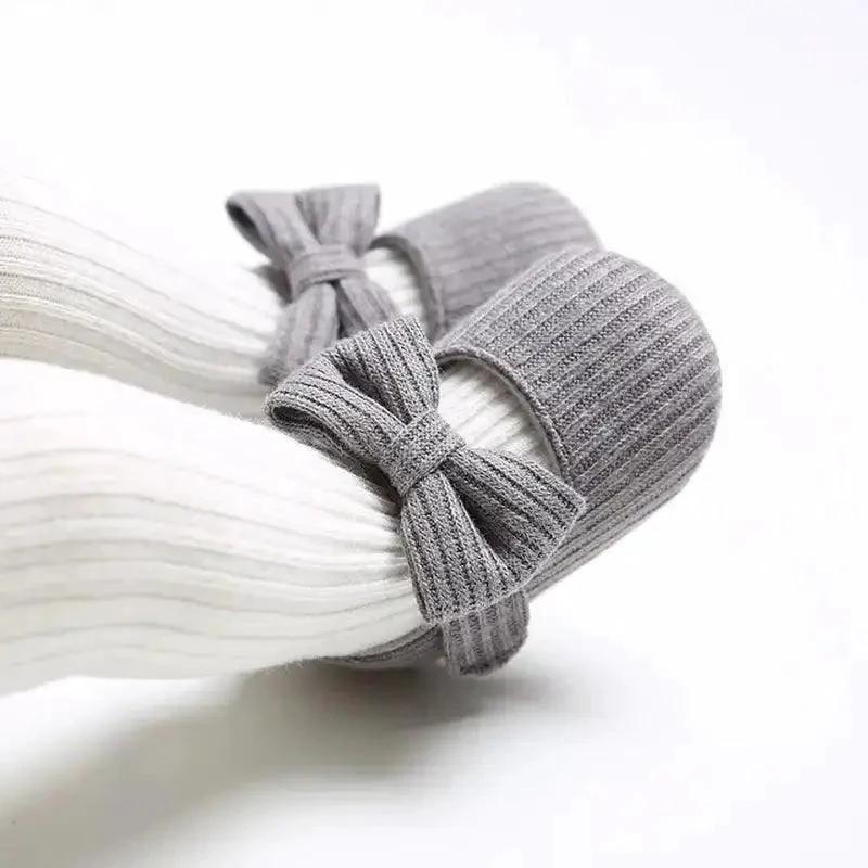 Soft newborn shoes by MANDOTOS featuring plush fabric and tiny soles, perfect for delicate baby feet.