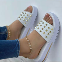 Pair of women's wedge rivet beach flip-flops in white with gold studs and chunky sole.