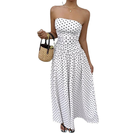 Polka-dot strapless maxi dress with ruched waist in white and black; paired with straw handbag.