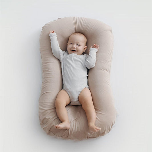 Baby nest bed in beige cotton, portable newborn travel cradle with cushioned sides