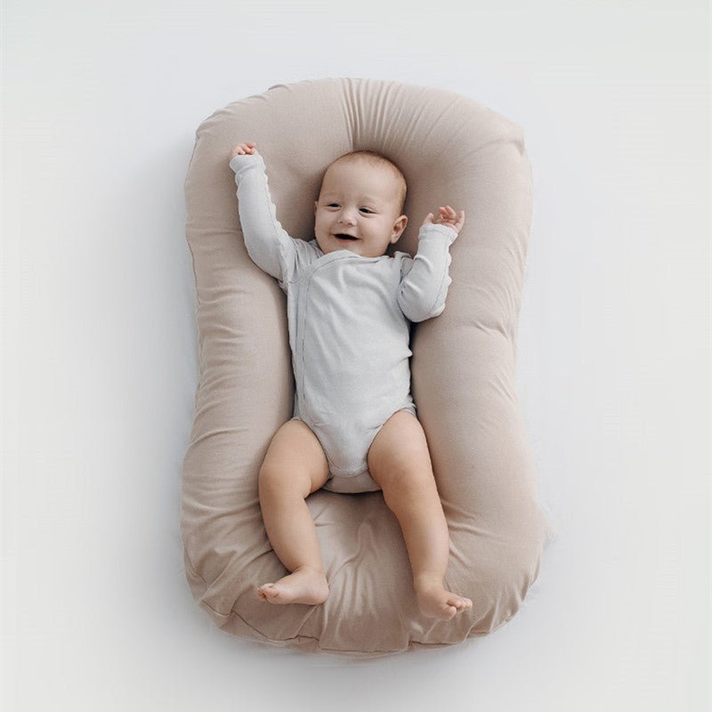 Baby nest bed in beige cotton, portable newborn travel cradle with cushioned sides