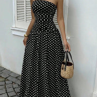 Polka-dot strapless maxi dress in black with white dots; ruched bodice and flowing skirt, with woven straw tote.