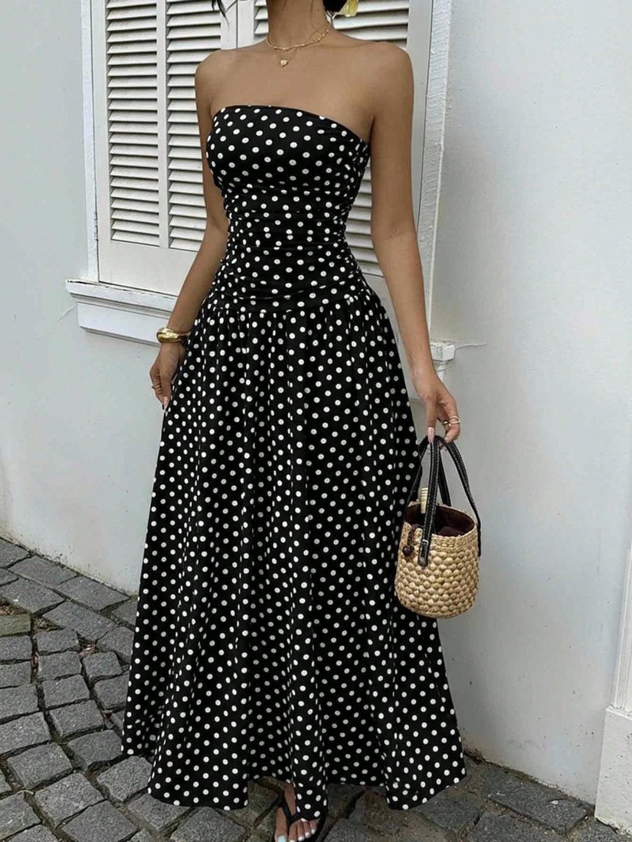 Polka-dot strapless maxi dress in black with white dots; ruched bodice and flowing skirt, with woven straw tote.