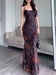 Flocked strappy maxi dress in black with red floral flocking, floor-length, worn by a model with a black handbag.