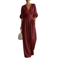 Jumpsuit, burgundy short-sleeve V-neck with wide-leg pants and wrapped waist belt, paired with a straw bag.