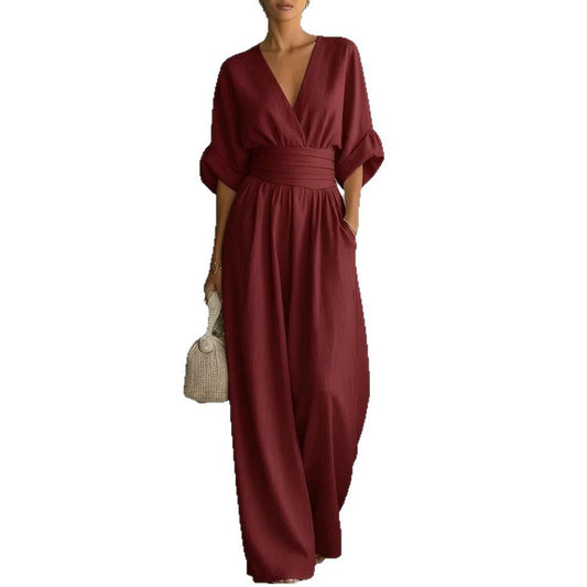 Jumpsuit, burgundy short-sleeve V-neck with wide-leg pants and wrapped waist belt, paired with a straw bag.