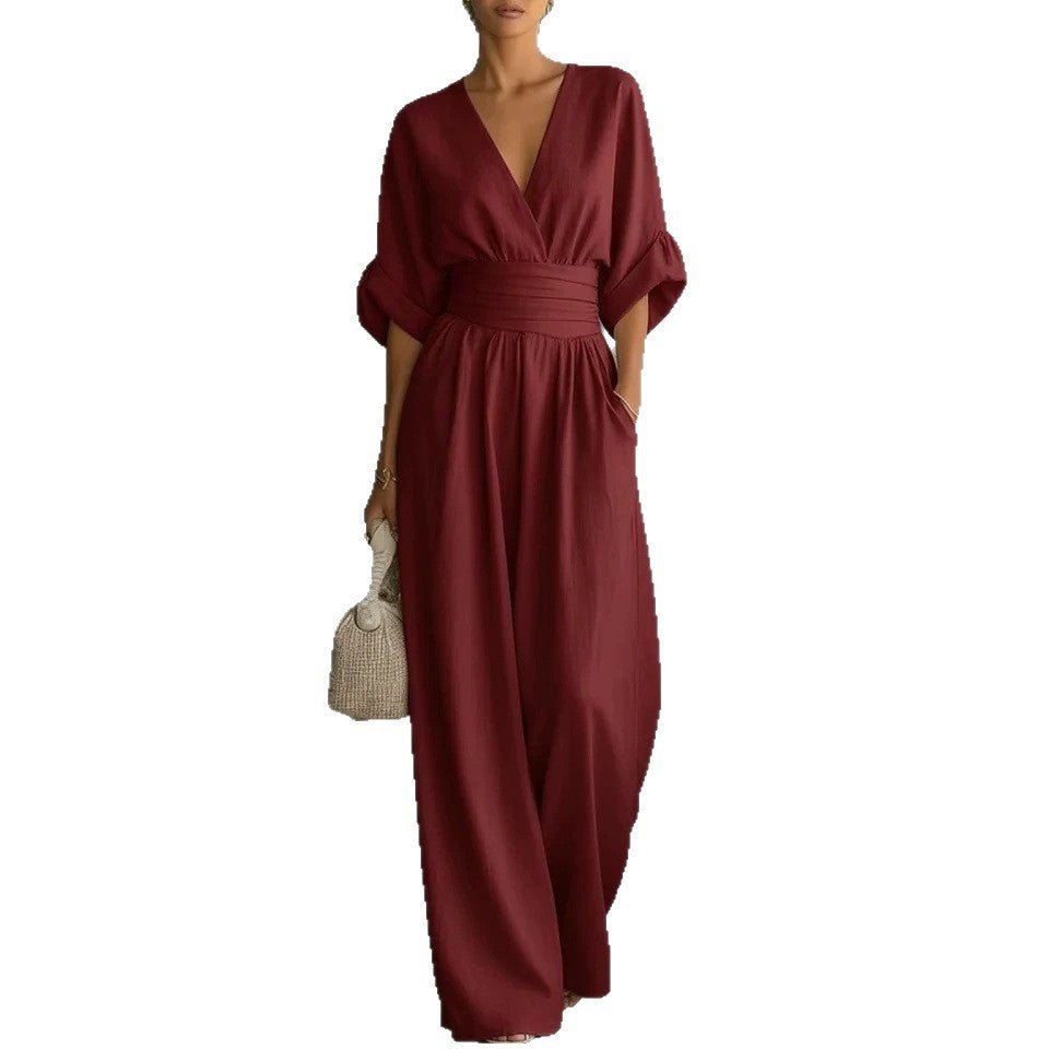 Jumpsuit, burgundy short-sleeve V-neck with wide-leg pants and wrapped waist belt, paired with a straw bag.