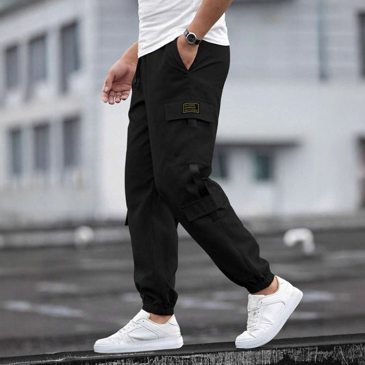 Mens retro jogger cargo pants in black with side flap pocket and yellow logo patch