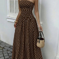 Polka-dot strapless maxi dress in brown with high-waist silhouette, paired with straw handbag