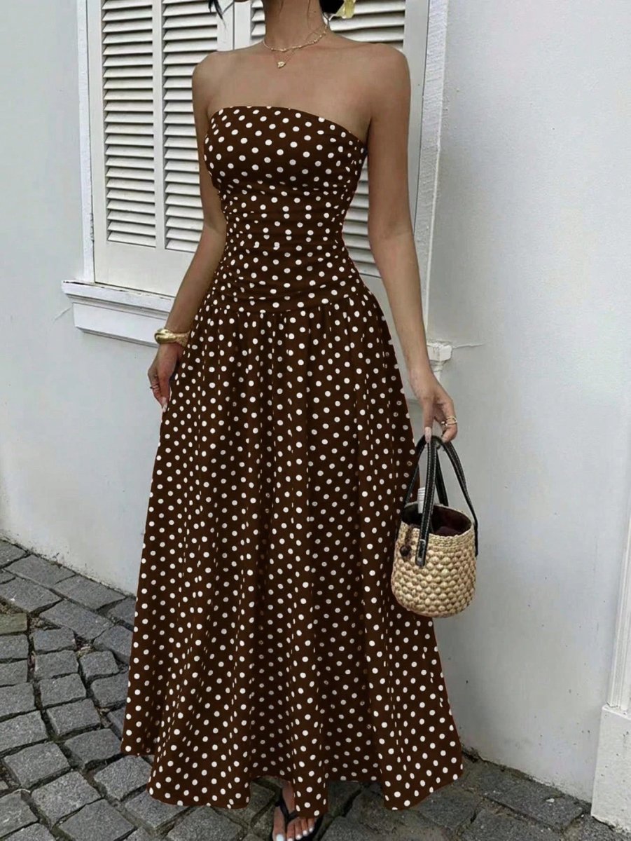 Polka-dot strapless maxi dress in brown with high-waist silhouette, paired with straw handbag