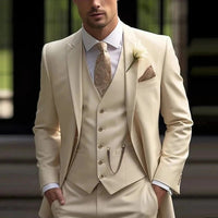 Mens cream slim-fit suit with vest, patterned beige tie, pocket square, and lapel flower