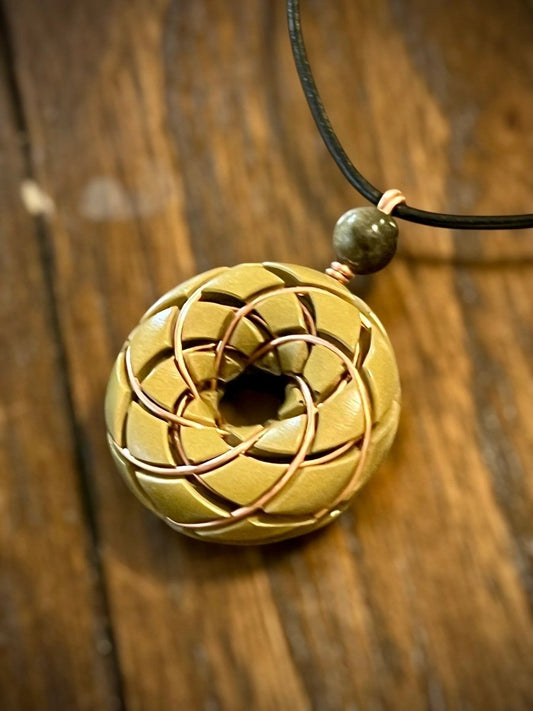 Brass Torus Vortex pendant with Libyan Desert Glass Orgonite necklace and Rodin Coil by Ancient Energy, close-up view of the jewelry piece.