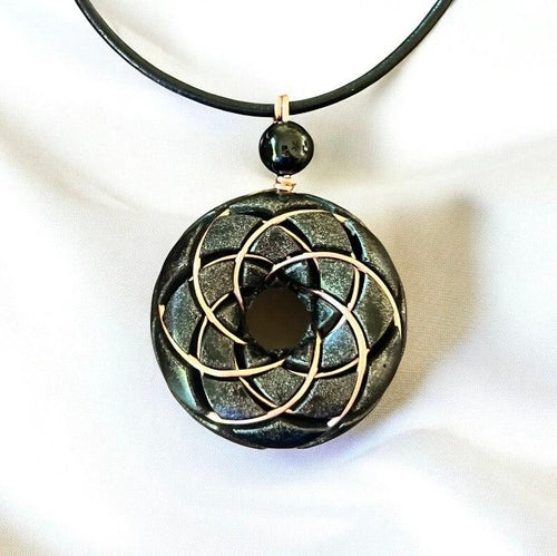 Ancient Energy Torus Vortex pendant necklace featuring Shungite orgonite and Rodin coil design, resting against a neutral background.