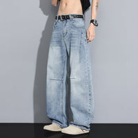 Men's denim jeans by Ancient Energy in light-wash, wide-leg fit with a black studded belt.