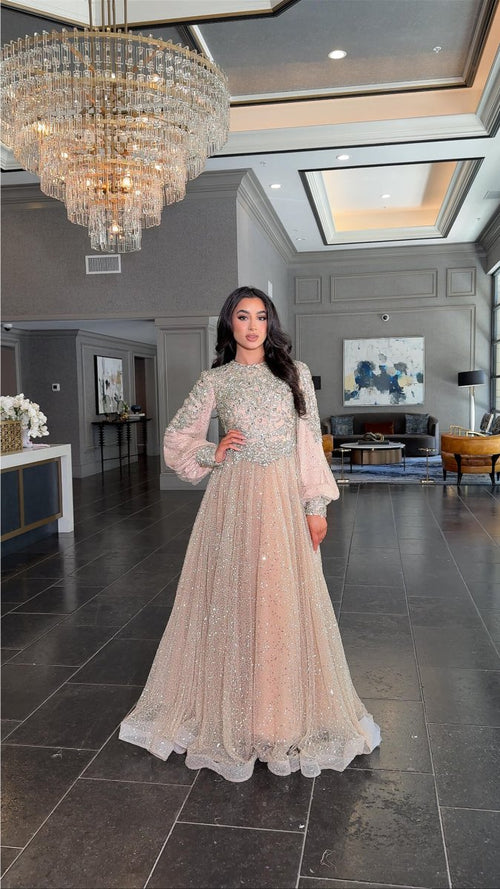 Iyza Belaar Bashira long sleeve embellished sequin modest ball gown, elegant evening dress with intricate beadwork and flowing fabric.