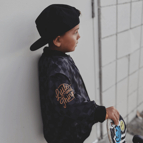 Kids waterproof letterman jacket by Little Rad Things with checkered pattern, featuring a warm, durable outer layer.