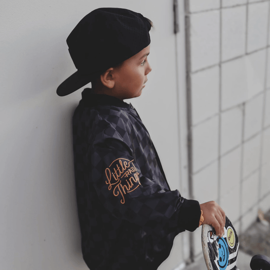 Kids waterproof letterman jacket by Little Rad Things with checkered pattern, featuring a warm, durable outer layer.