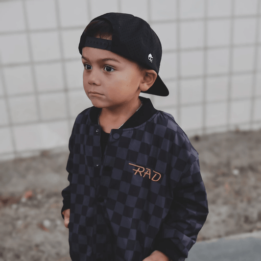 Kids waterproof letterman jacket by Little Rad Things with checkered pattern, featuring a durable, stylish design for outdoor wear.