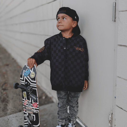 Kids waterproof letterman jacket by Little Rad Things with checkered design, featuring a sporty style and vibrant colors.