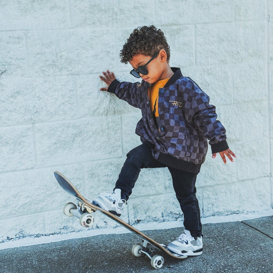 Kids waterproof letterman jacket by Little Rad Things with a checkers pattern and ribbed cuffs, perfect for rainy days.