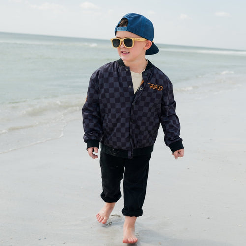Kids waterproof letterman jacket by Little Rad Things with checkered pattern, featuring a sporty, colorful design.
