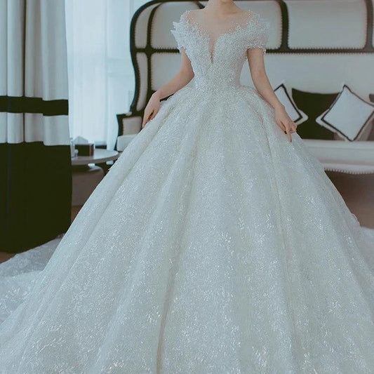 Off-shoulder French main wedding dress by MANDOTOS featuring elegant lace details and a flowing train.