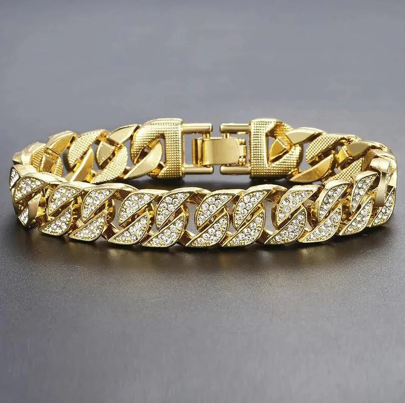 Close-up of a gold Cuban curb bracelet by MANDOTOS featuring interlinked flat chain links on a neutral background.