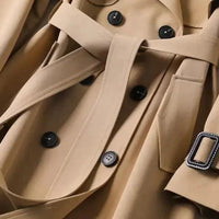 Mandotos elegant classic trench coat displayed on a hanger, featuring a timeless design and neutral color for sophisticated style.