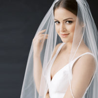 Long flowing wedding veil by MANDOTOS with delicate lace edging and sheer tulle fabric, designed for elegant bridal looks.