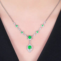 Mandotos Emerald Elegance white gold necklace with a central emerald gemstone and delicate chain design.