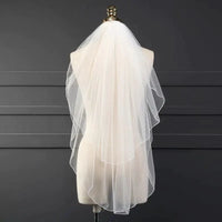 Ethereal double-tiered veil by MANDOTOS featuring delicate lace and soft tulle layers for a graceful bridal look.