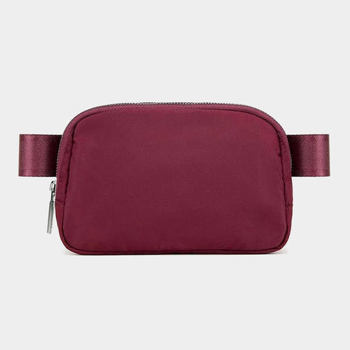 Mandotos International lightweight women's waist bag for running and travel, shown in black with adjustable strap and secure zipper.