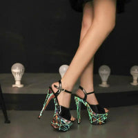 Pair of shiny black leather stilettos from MANDOTOS with pointed toes and high heels, displayed on a neutral background.