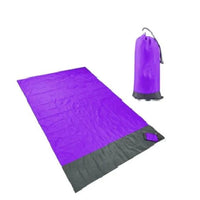 Mandotos sandproof portable beach mat spread out on sandy beach with colorful towel and blue sky.