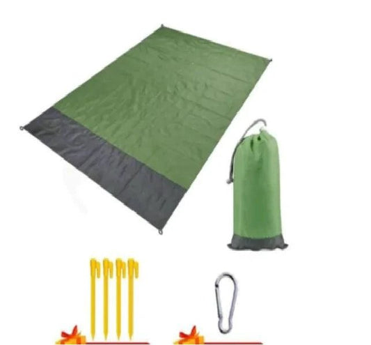 Mandotos sandproof portable beach mat spread out on sandy beach with blue sky in the background.