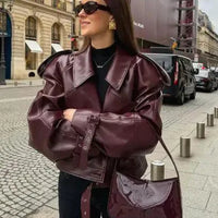 Mandotos sleek matte leather coat displayed on a hanger, showcasing its smooth texture and modern design.