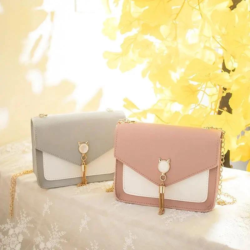 Small women's crossbody bag by MANDOTOS featuring a cat lock chain design and compact messenger style.
