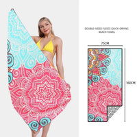 Mandotos SwiftDry patterned beach towel with colorful geometric design laid out on sandy beach.